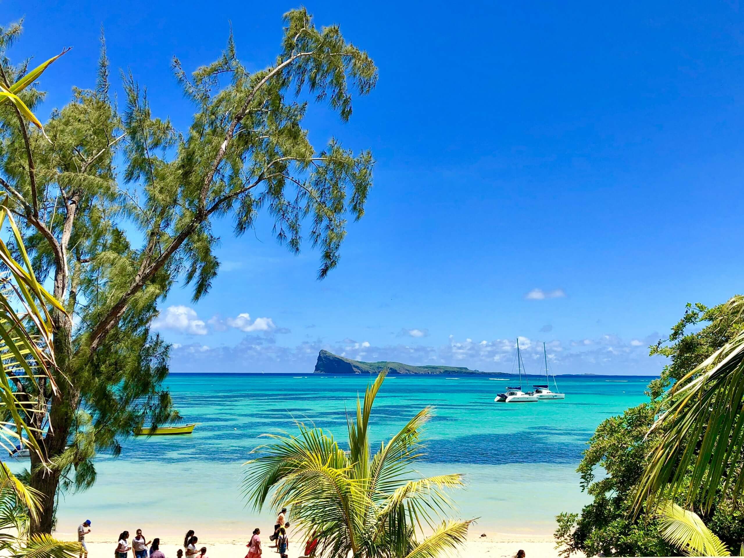 Tropical island beach with 2 catamarans in clean blue water